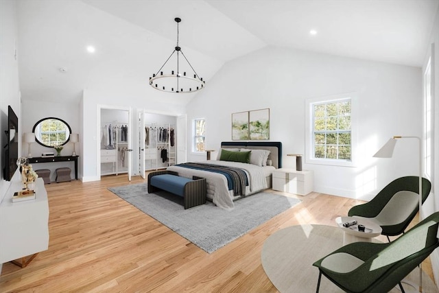 bedroom featuring ensuite bathroom, a walk in closet, high vaulted ceiling, and light hardwood / wood-style flooring