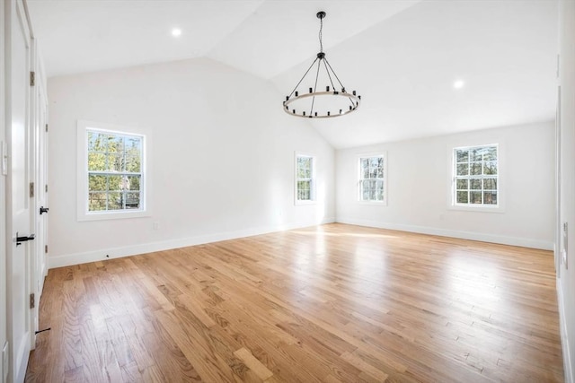 spare room with vaulted ceiling, a wealth of natural light, and light hardwood / wood-style flooring