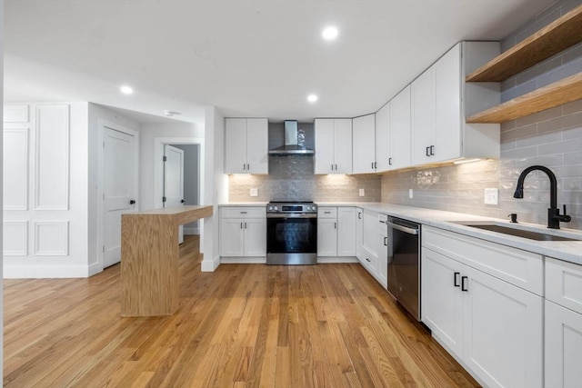 kitchen featuring decorative backsplash, sink, stainless steel appliances, white cabinets, and wall chimney exhaust hood