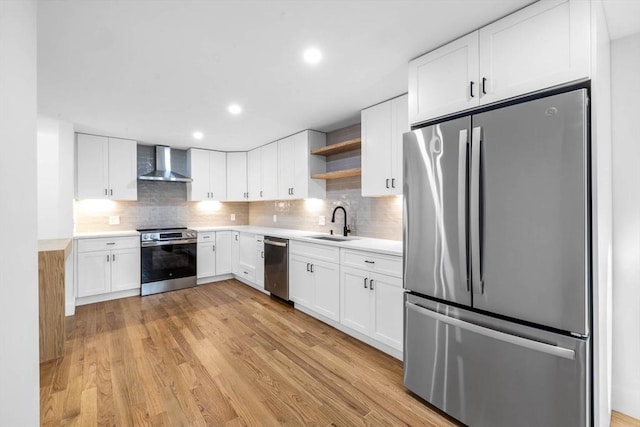 kitchen featuring white cabinets, appliances with stainless steel finishes, light hardwood / wood-style flooring, and wall chimney exhaust hood