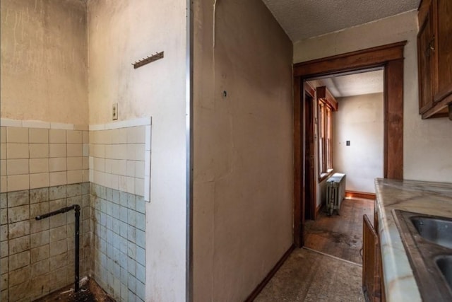 bathroom with sink, a textured ceiling, radiator, and tile walls