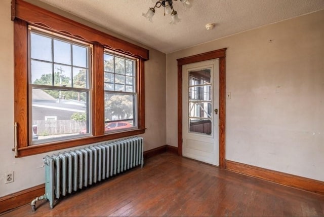 interior space featuring hardwood / wood-style flooring, radiator heating unit, and a textured ceiling