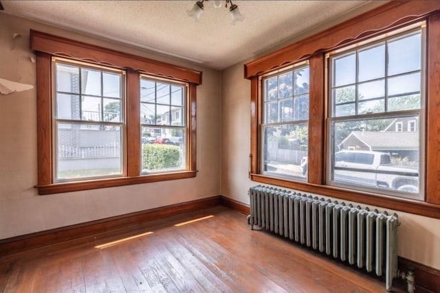 interior space featuring wood-type flooring, radiator heating unit, and a textured ceiling