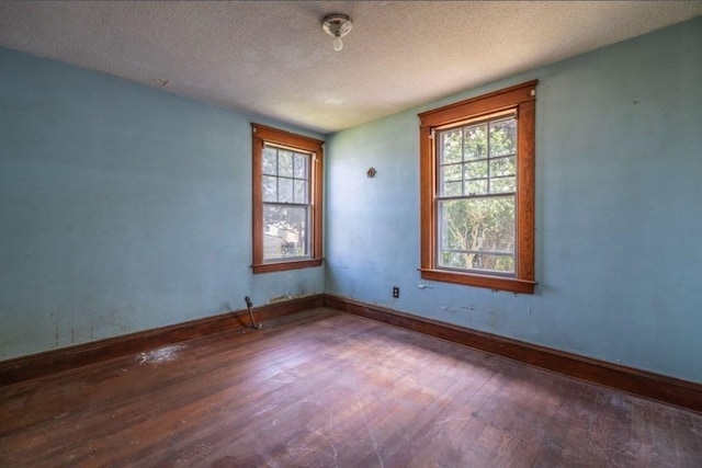 unfurnished room with a textured ceiling and dark hardwood / wood-style floors