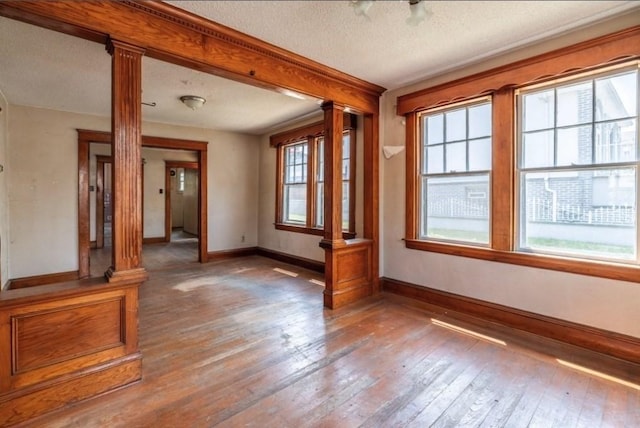 interior space with decorative columns, hardwood / wood-style flooring, and a textured ceiling