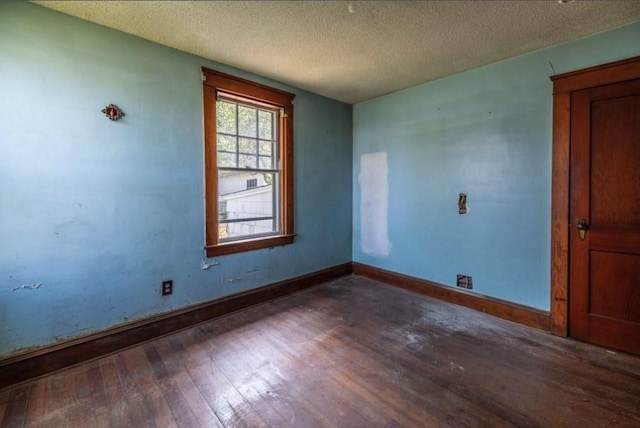 empty room featuring dark wood-type flooring and a textured ceiling