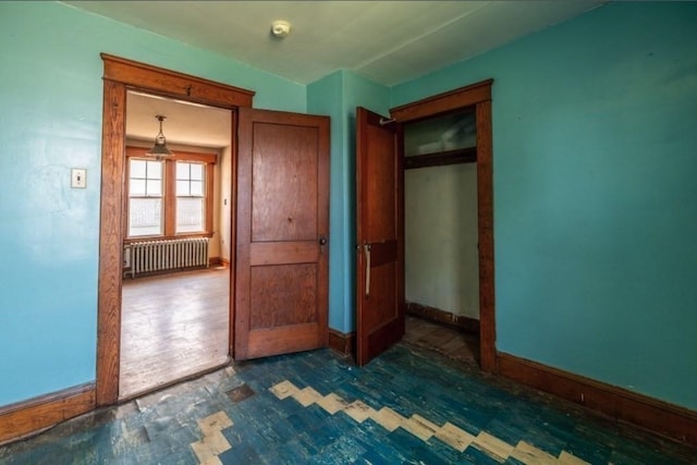 unfurnished bedroom with radiator and a closet