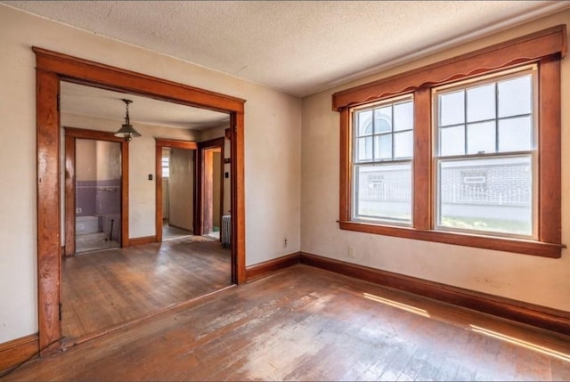 unfurnished room featuring dark wood-type flooring, a textured ceiling, and radiator