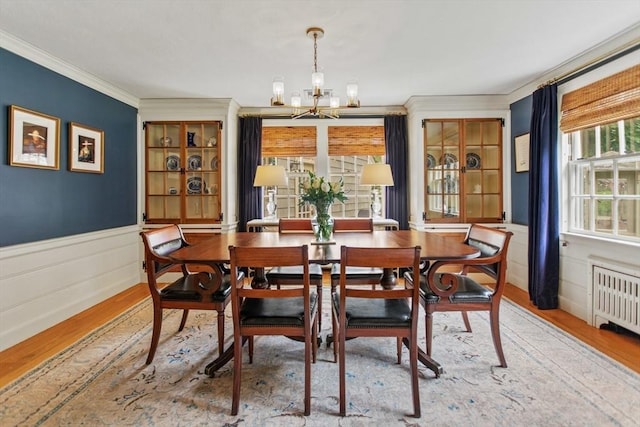 114 Chestnut St, North Reading, MA 01864 - dining room featuring radiator heating unit, a chandelier, light wood-style flooring, crown molding, and wainscoting