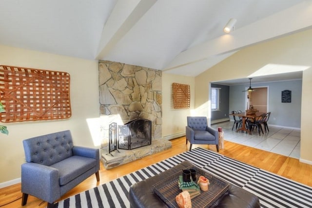 living room featuring vaulted ceiling, a baseboard radiator, a fireplace, and light hardwood / wood-style flooring