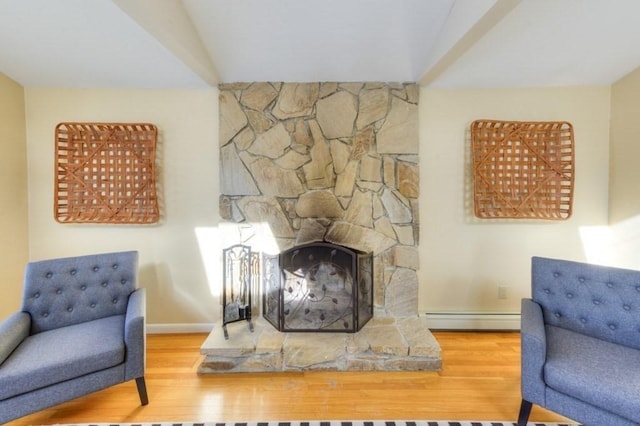 living room featuring hardwood / wood-style flooring, a stone fireplace, and a baseboard heating unit