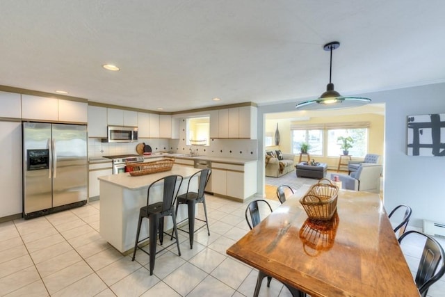 kitchen with tasteful backsplash, light tile patterned floors, a kitchen island, stainless steel appliances, and white cabinets