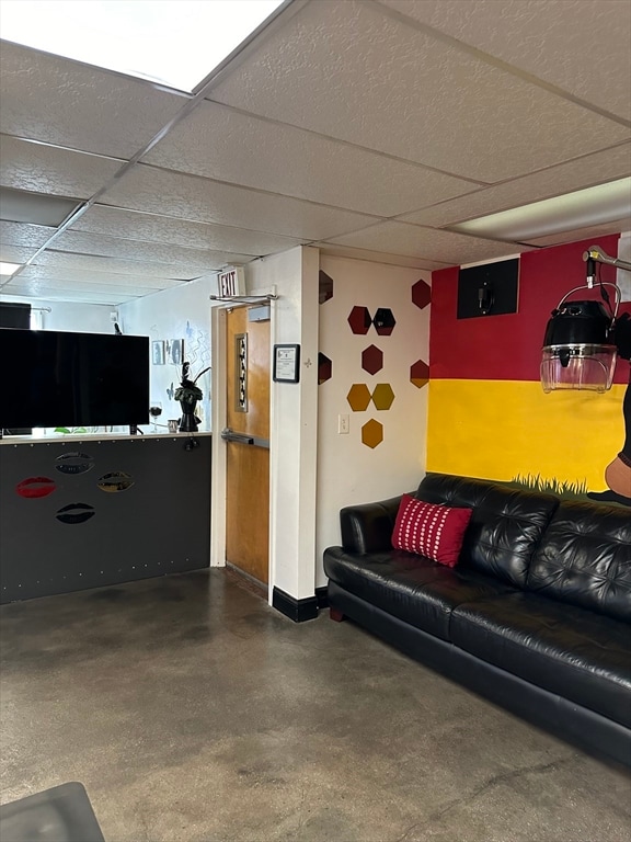 living room with a drop ceiling and concrete flooring