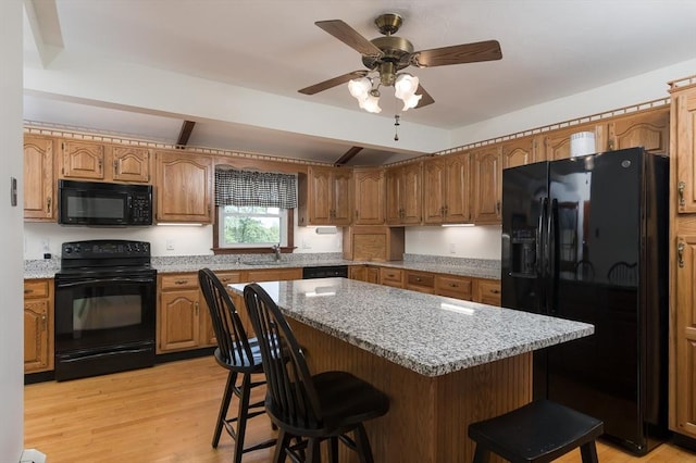 20 Blaine Ave, Worcester, MA 01603 - kitchen with black appliances, a breakfast bar area, light wood-type flooring, a kitchen island, and brown cabinetry