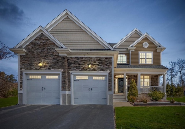 view of front of property featuring a front yard, driveway, a porch, stone siding, and a garage