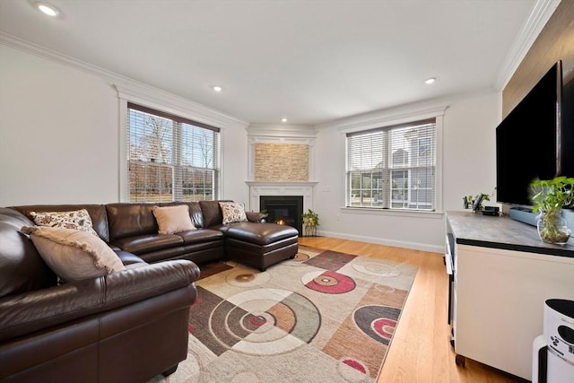 living room with a glass covered fireplace, recessed lighting, light wood-type flooring, and ornamental molding