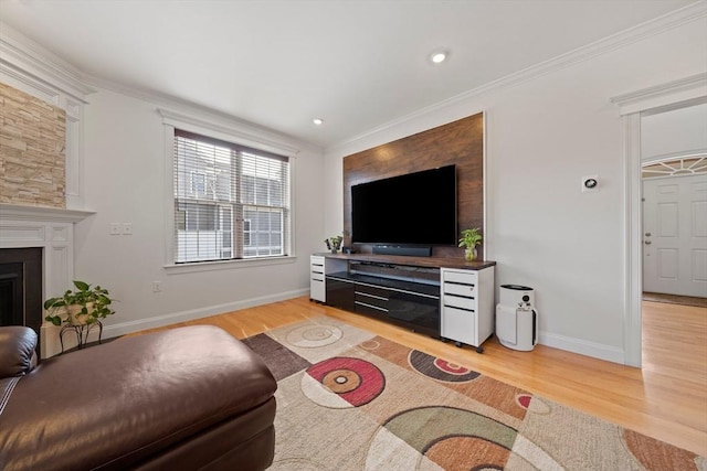 living area with baseboards, light wood-style floors, a fireplace, and crown molding