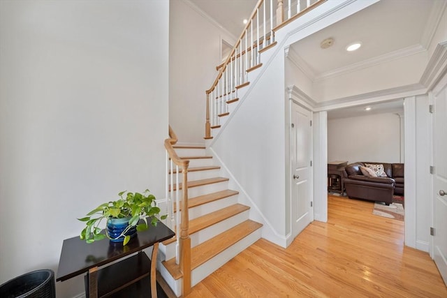 stairway with recessed lighting, wood finished floors, baseboards, and ornamental molding