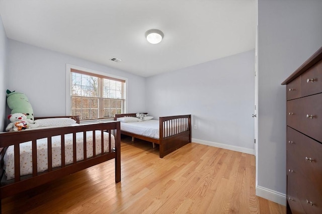 bedroom featuring light wood finished floors, visible vents, and baseboards