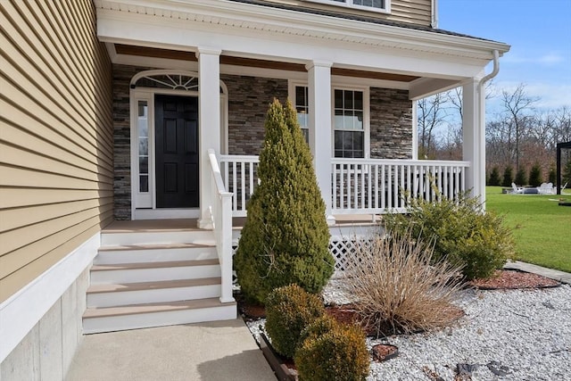 view of exterior entry featuring stone siding and covered porch