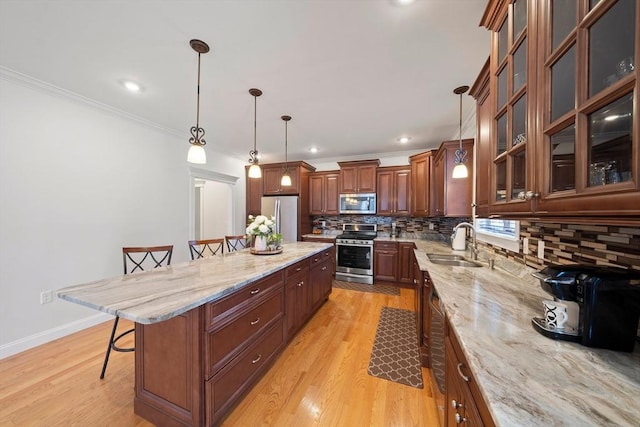 kitchen with light stone counters, light wood finished floors, a breakfast bar, a sink, and stainless steel appliances