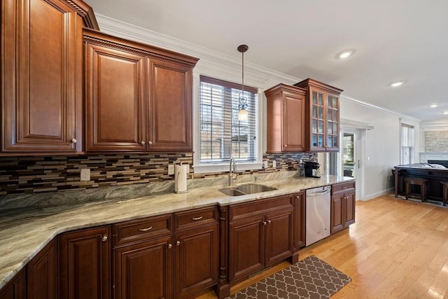 kitchen featuring a sink, crown molding, light wood-style flooring, hanging light fixtures, and stainless steel dishwasher