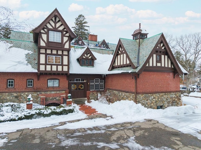 tudor-style house featuring stone siding, stucco siding, and brick siding