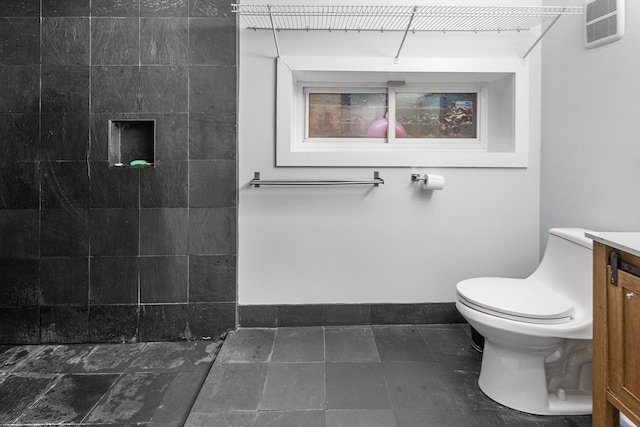 bathroom featuring toilet, a shower, and vanity