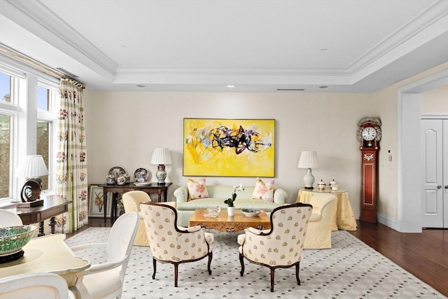 dining area with a raised ceiling, crown molding, wood finished floors, and baseboards