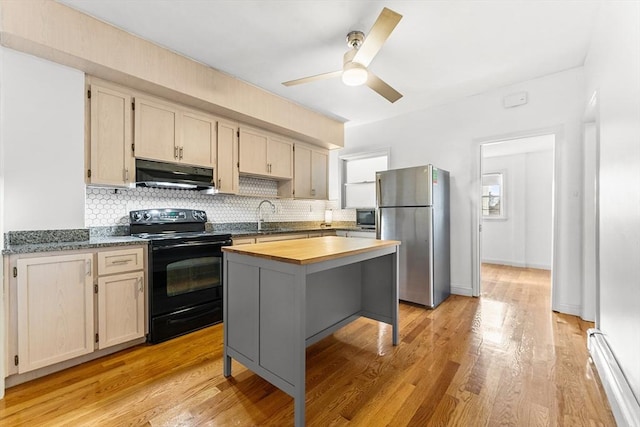 kitchen with a baseboard heating unit, under cabinet range hood, butcher block countertops, freestanding refrigerator, and black electric range oven