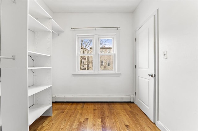 spacious closet featuring baseboard heating and wood finished floors