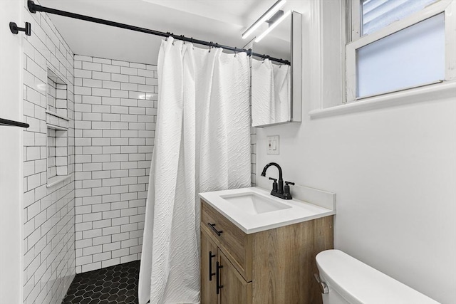 full bathroom featuring a tile shower, toilet, and vanity