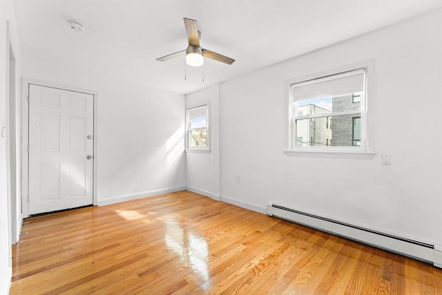 unfurnished room featuring a baseboard radiator, baseboards, ceiling fan, and light wood finished floors