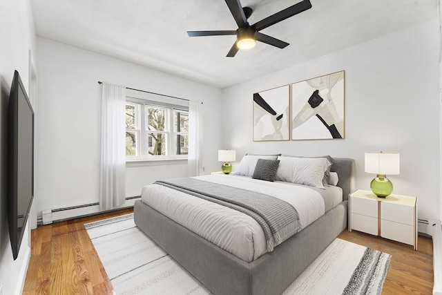 bedroom with a ceiling fan, light wood-style floors, and baseboard heating