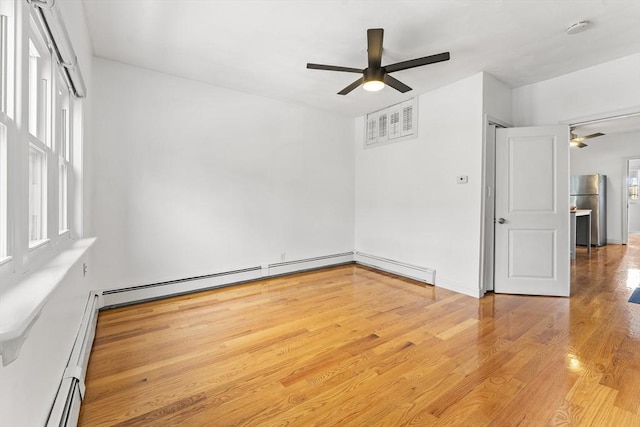 empty room featuring a baseboard radiator, a ceiling fan, and wood finished floors