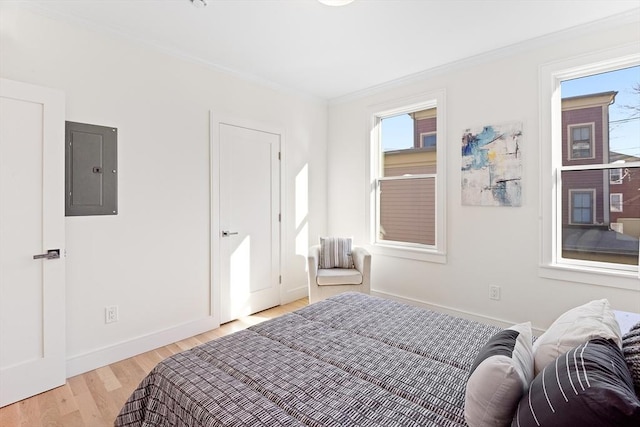 bedroom featuring electric panel, crown molding, and light wood-type flooring