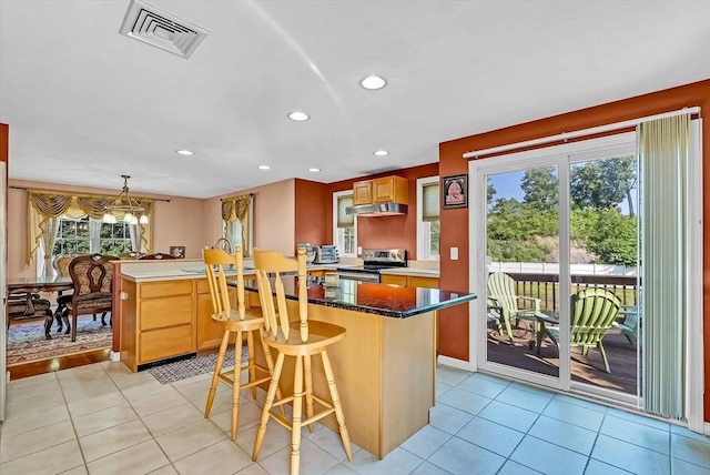 kitchen featuring light tile patterned floors, stainless steel electric range oven, decorative light fixtures, and a kitchen bar