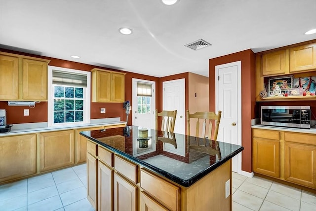 kitchen with a healthy amount of sunlight, dark stone counters, and a kitchen island