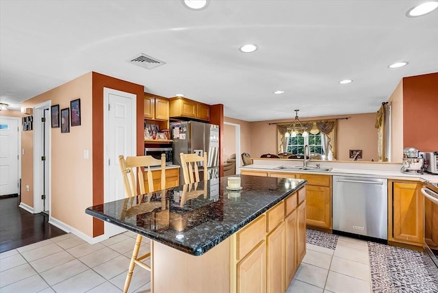 kitchen featuring kitchen peninsula, a kitchen bar, sink, appliances with stainless steel finishes, and light tile patterned floors