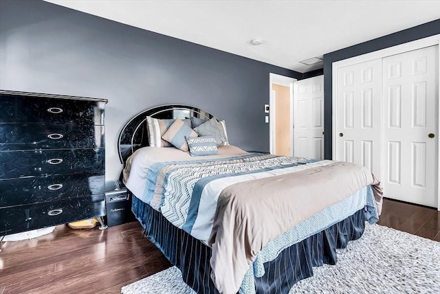 bedroom with dark hardwood / wood-style flooring and a closet