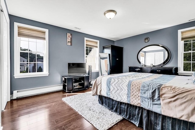 bedroom with dark wood-type flooring and a baseboard heating unit