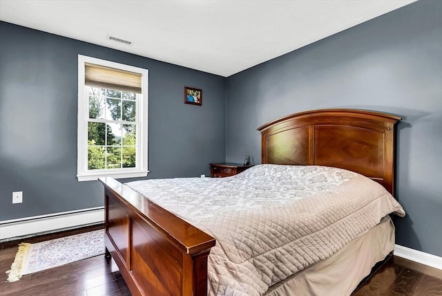 bedroom featuring a baseboard heating unit and dark hardwood / wood-style floors