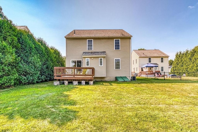 back of property featuring a deck, a lawn, and central AC