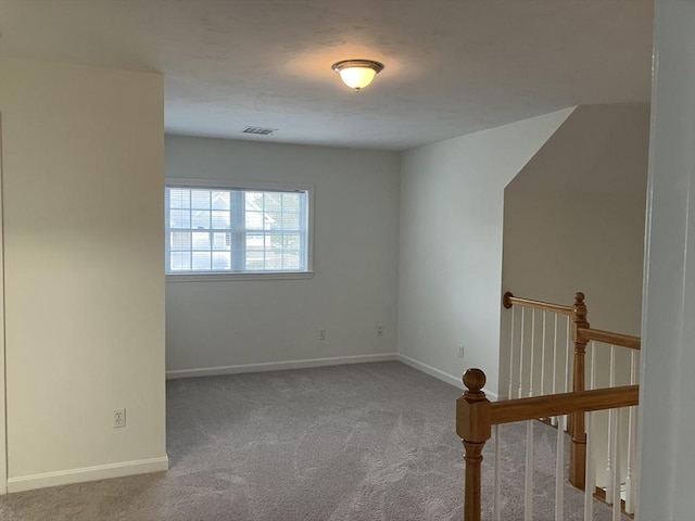 carpeted spare room featuring visible vents and baseboards