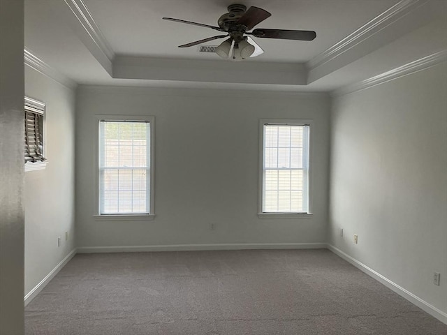 carpeted spare room featuring a healthy amount of sunlight, baseboards, a tray ceiling, and ornamental molding