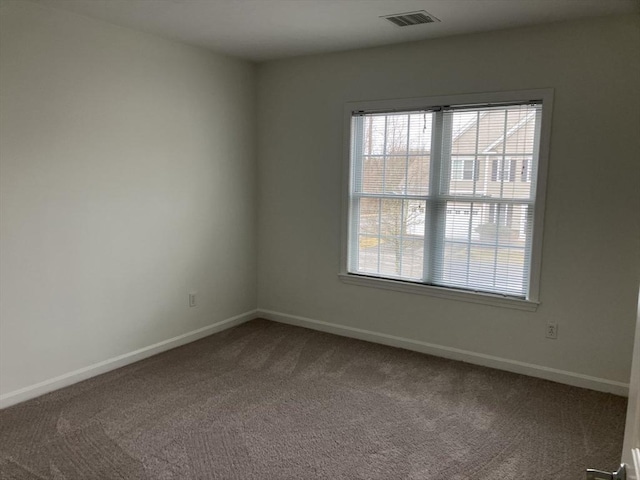 unfurnished room with carpet, visible vents, and baseboards