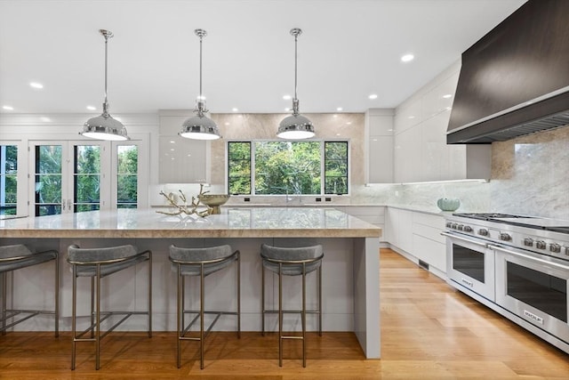 kitchen with double oven range, modern cabinets, island range hood, and white cabinets