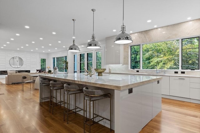 kitchen featuring light stone counters, decorative light fixtures, a large island, white cabinetry, and modern cabinets