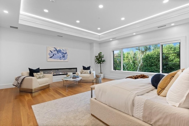 bedroom with light wood-type flooring, a glass covered fireplace, visible vents, and recessed lighting