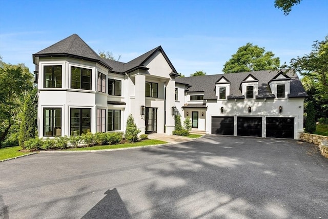 view of front facade with a garage, aphalt driveway, a shingled roof, and stucco siding